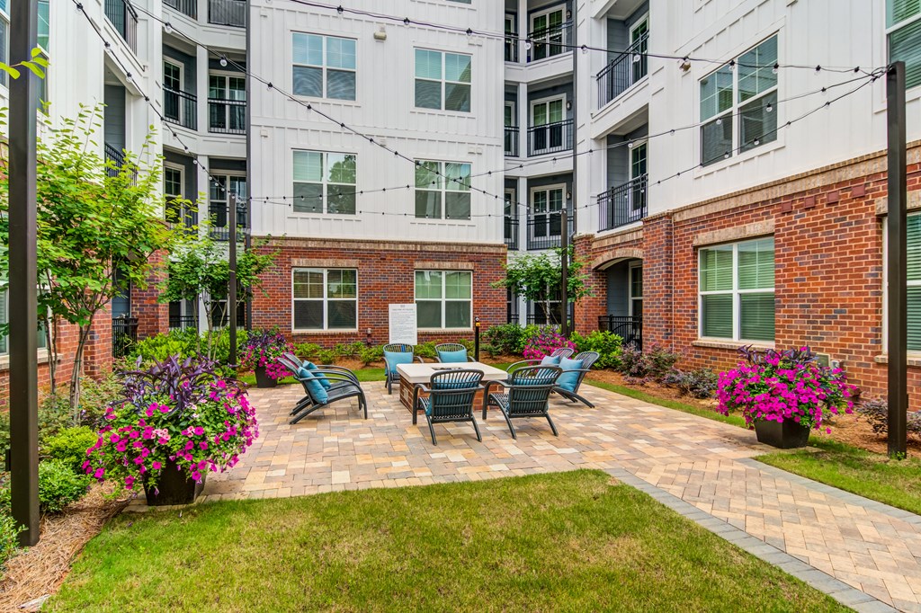 a patio with a table and chairs in front of an apartment building