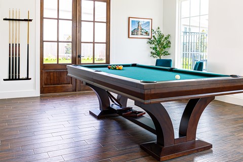 A pool table with a green felt cloth and white balls is in the center of the room.