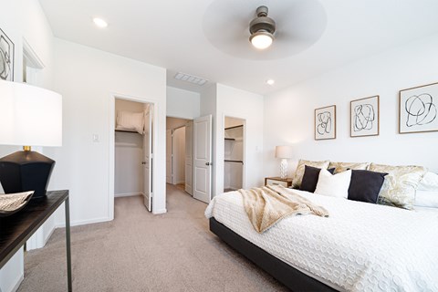 A bedroom with a large bed and a lamp on a side table.