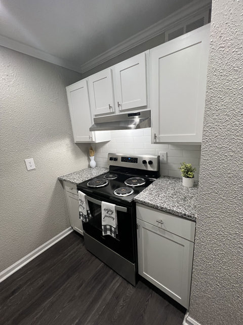 a small kitchen with white cabinets and a stove and oven