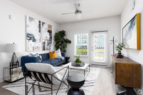 A living room with a blue couch and a white chair.