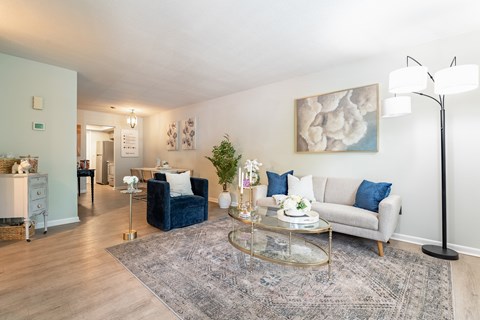 A living room with a blue sofa and a glass coffee table.