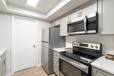 A modern kitchen with a stainless steel refrigerator, oven, and microwave.