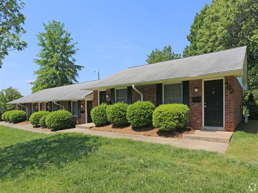 the front of a brick house with a lawn and bushes at Four Seasons Villas, Greensboro