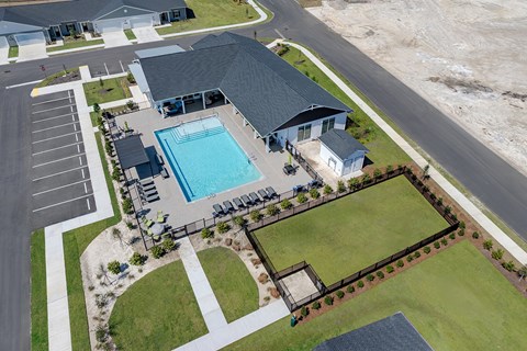 A large swimming pool is surrounded by a small building and a grassy area.