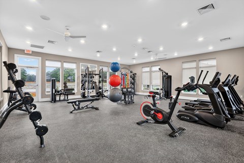 A spacious gym with a variety of equipment including a stationary bike, dumbbells, and a medicine ball.