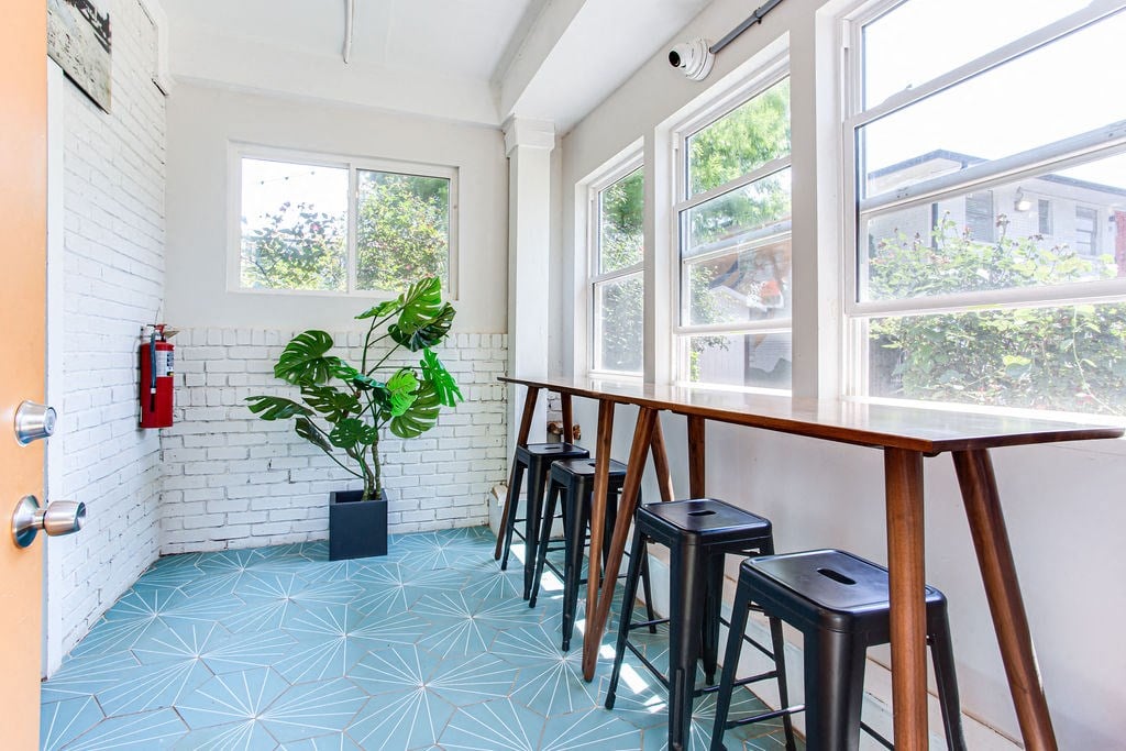 a long wooden table with black stools in a white room with large windows  at The Oasis on Cascade, Atlanta, GA