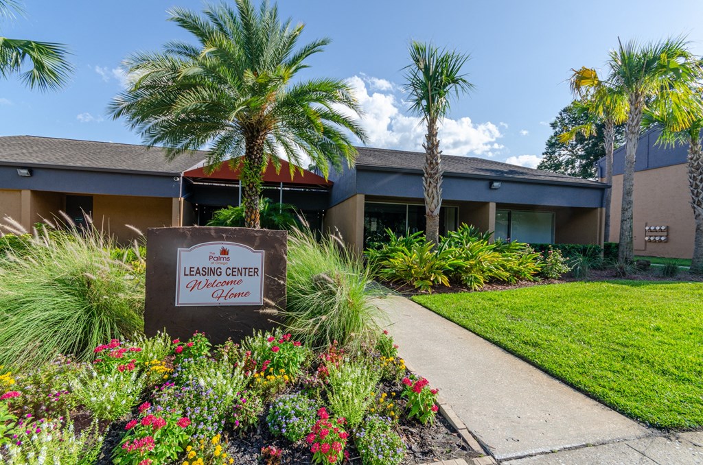 a sidewalk in front of a building with palm trees