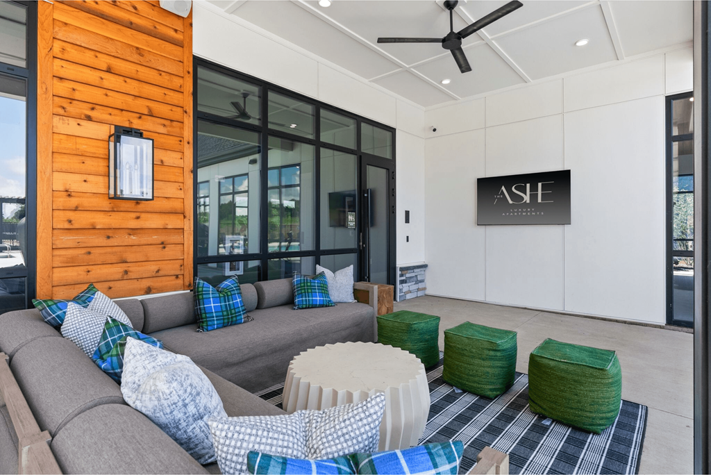 A living room with a grey couch and a wooden wall.