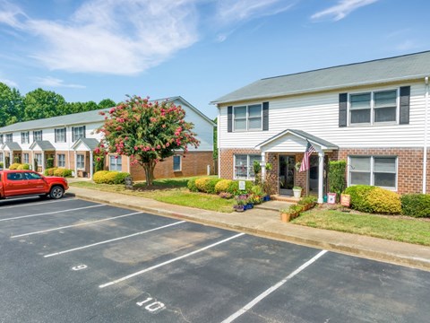 a red car parked in a parking lot in front of a house