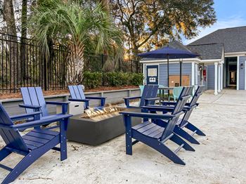 A set of blue chairs and a fire pit are arranged on a concrete surface.