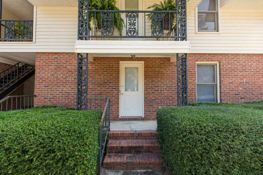A house with a white door and a staircase leading to the second floor.