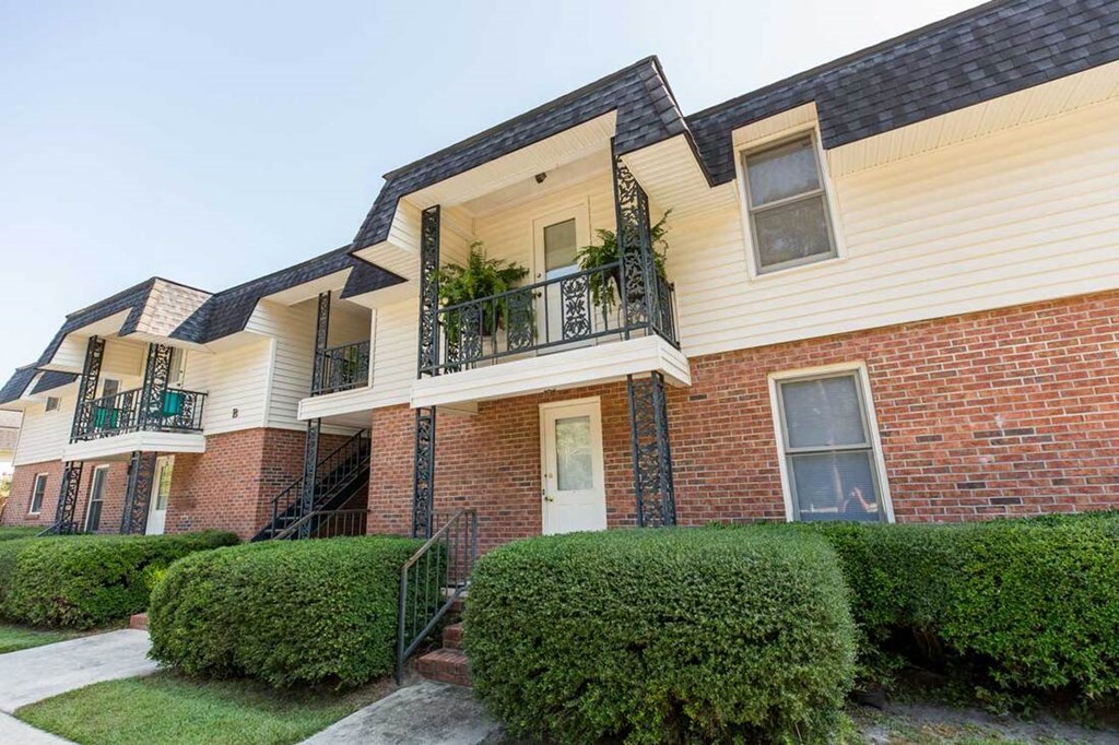 A two-story brick house with a balcony and a black railing.