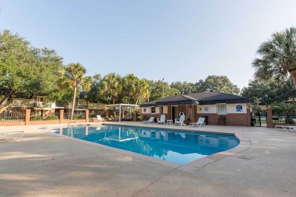A swimming pool surrounded by palm trees and a building.