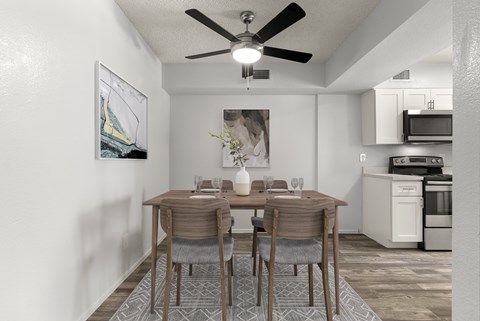 A dining room with a table set for two and a ceiling fan.