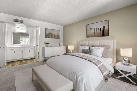 A bedroom with a large bed and a bench in front of it.