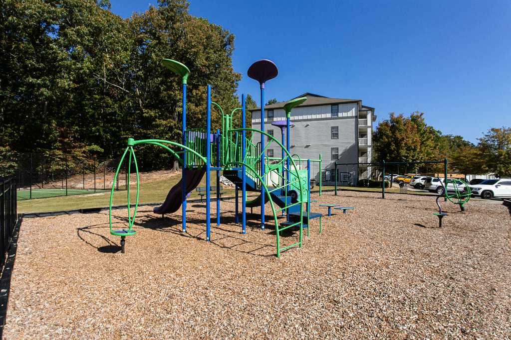 a playground at a park with a building in the background  at Peaks at Gainesville, Gainesville, 30507