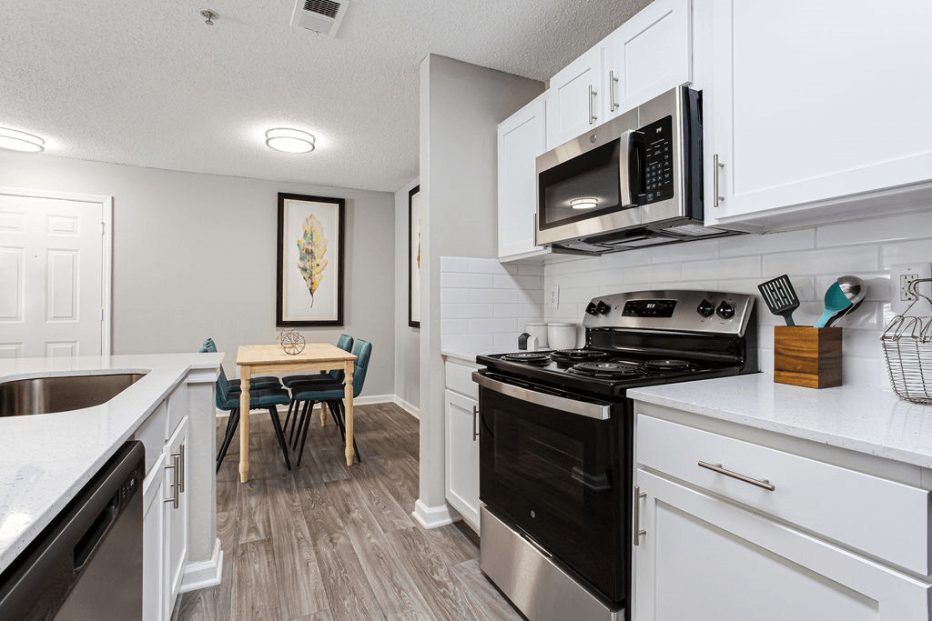 a renovated kitchen with white cabinets and black appliances and a dining room table  at Peaks at Gainesville, Gainesville, Georgia