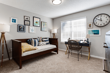a bedroom with a bed and a desk with a clock on the wall at Peaks at Gainesville, Gainesville, GA