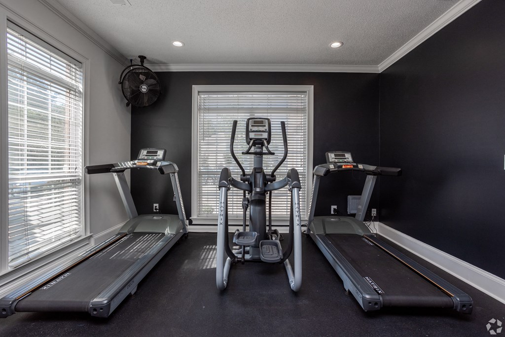 a home gym with three treadmills and a window