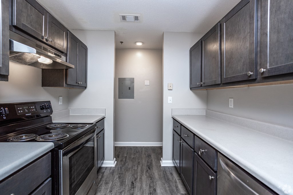 an empty kitchen with stainless steel appliances and dark wood cabinets