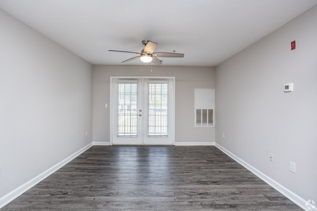 an empty living room with white walls and a ceiling fan