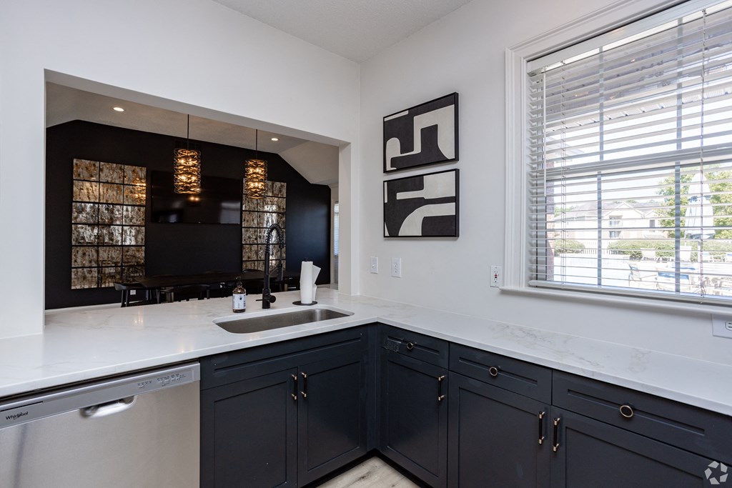 a kitchen with black and white cabinets and a sink and a window