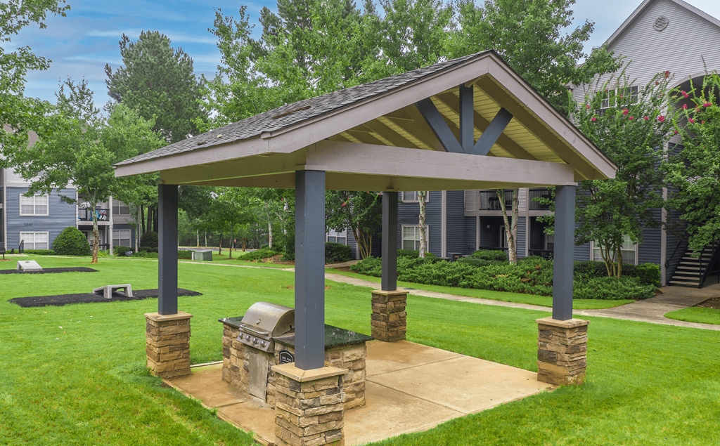 a pavilion with a grill in the middle of a grassy area