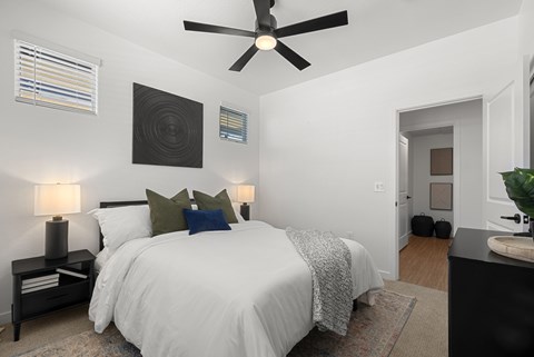 A bedroom with a white bed and a ceiling fan.