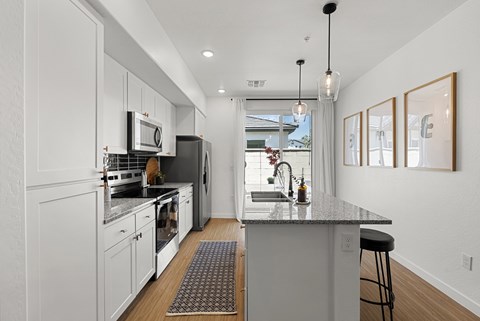 A kitchen with white cabinets and a black countertop.