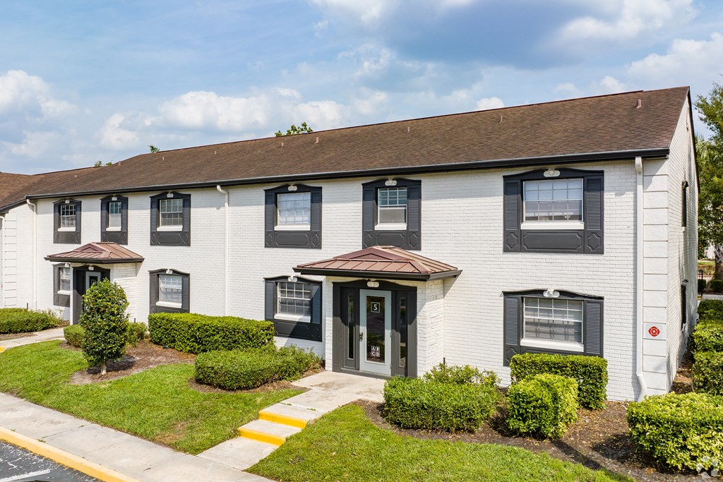 a white building with black shuttered windows and a lawn at The Essex, Florida, 32701