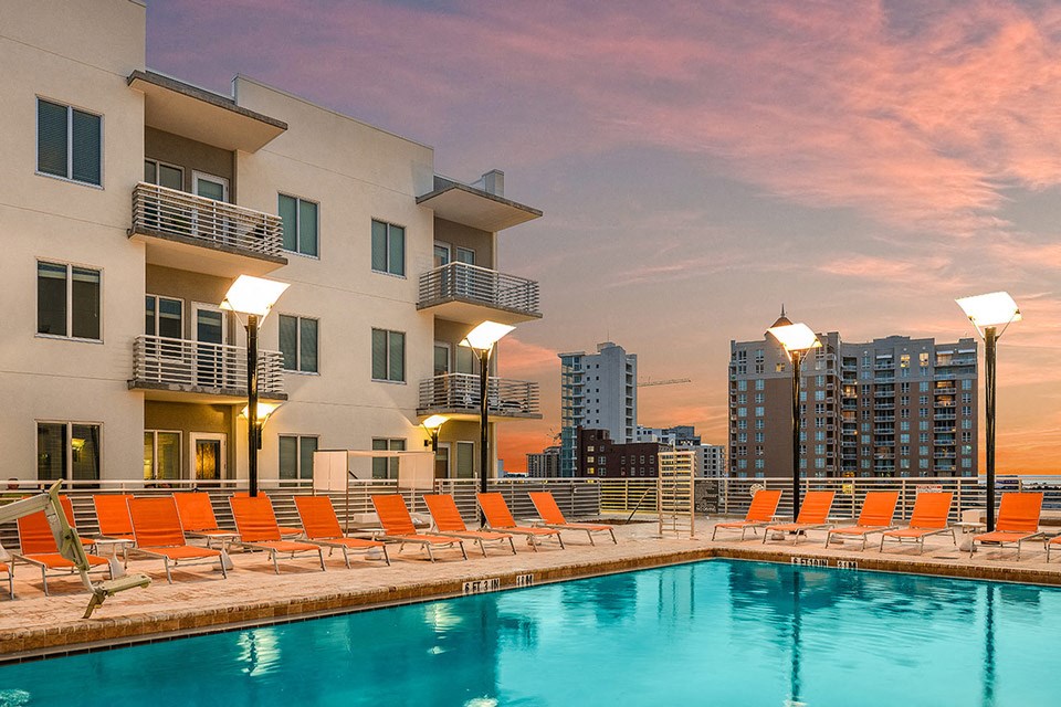 a swimming pool at an apartment building in the city at sunset
