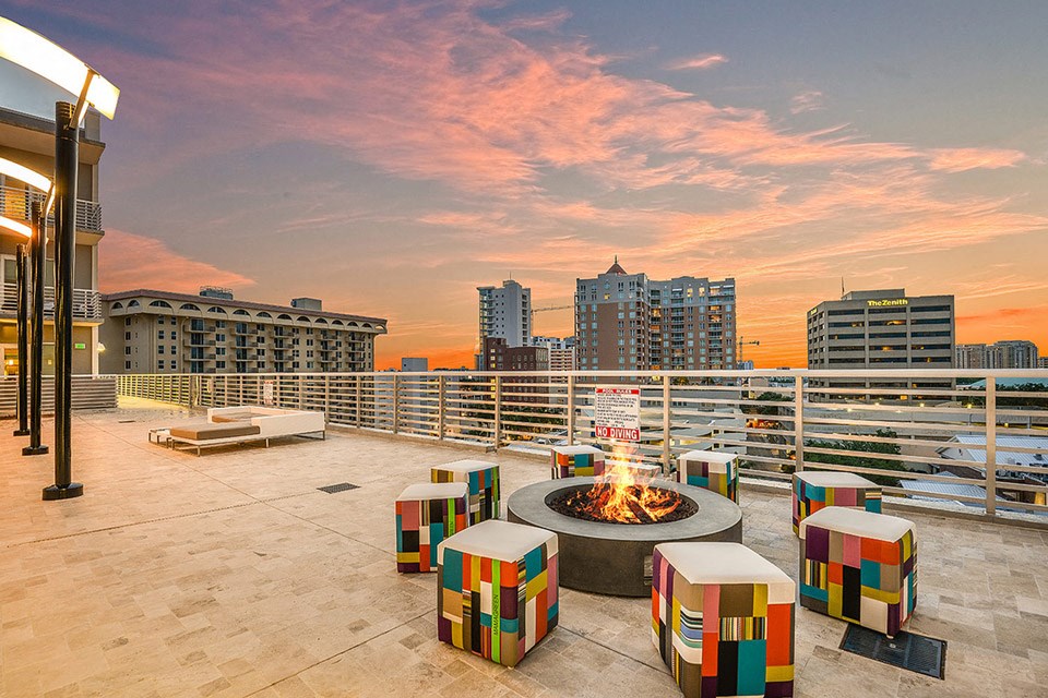 a fire pit on the roof of a building with the city in the background