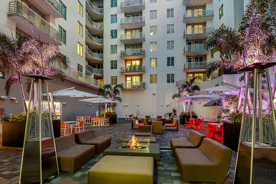 a lounge area with chairs and umbrellas in front of an apartment building
