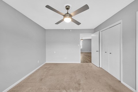 an empty room with a ceiling fan and a closet