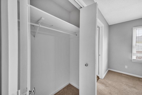 the living room of an apartment with white walls and a door to a closet