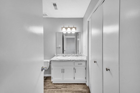 a bathroom with white cabinets and a sink and a mirror