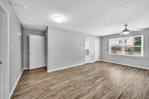 an empty living room with a window and a ceiling fan