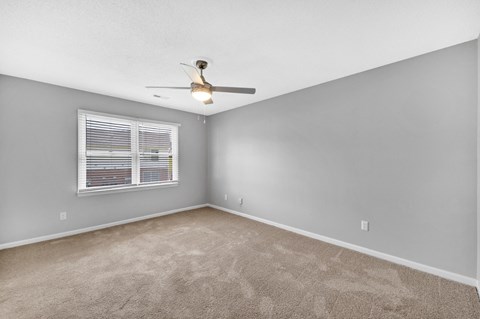 an empty bedroom with a ceiling fan and a window