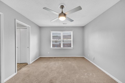 an empty room with a ceiling fan and a window