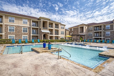 A large swimming pool in front of apartment buildings.