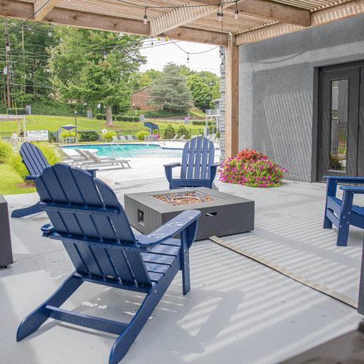a patio with blue chairs and a fire pit and a pool