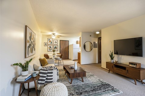 A living room with a grey and white striped ottoman in front of a wooden coffee table.
