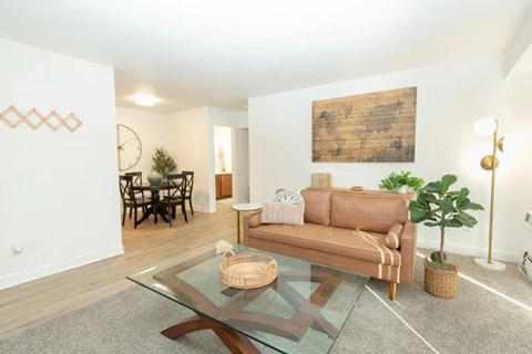 A living room with a brown sofa and a glass coffee table.