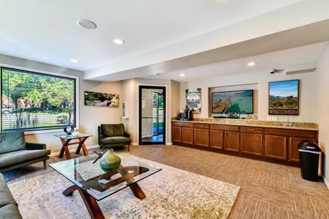 A living room with a glass coffee table and a green vase on it.