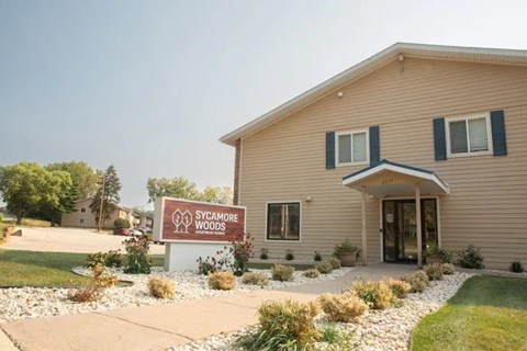 A building with a sign that says Sycamore Woods in front of it.