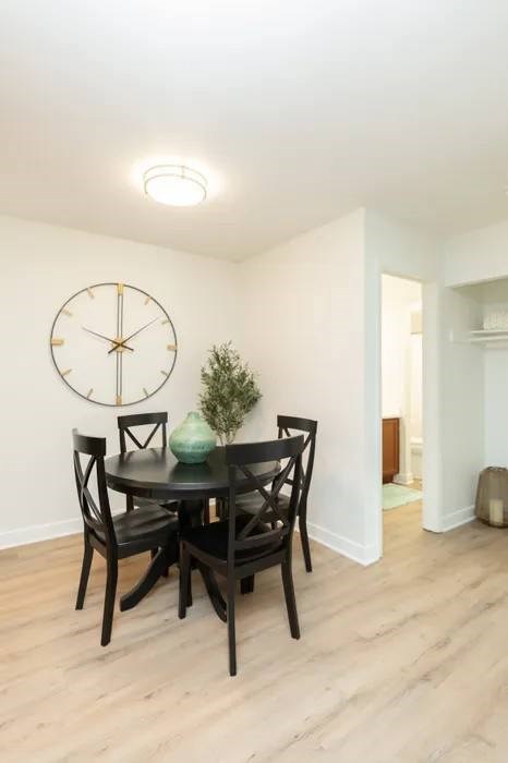 A dining room with a round table and chairs and a clock on the wall.