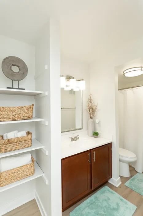 A bathroom with a white sink and brown cabinets.