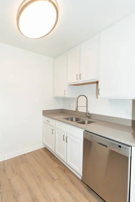A kitchen with white cabinets and a wooden floor.