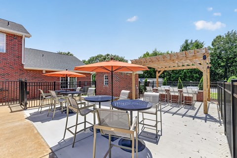 A patio with a table and chairs under an orange umbrella.